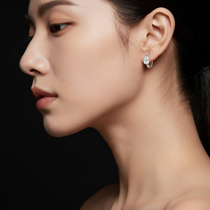 Model wearing pear solitaire huggie earrings