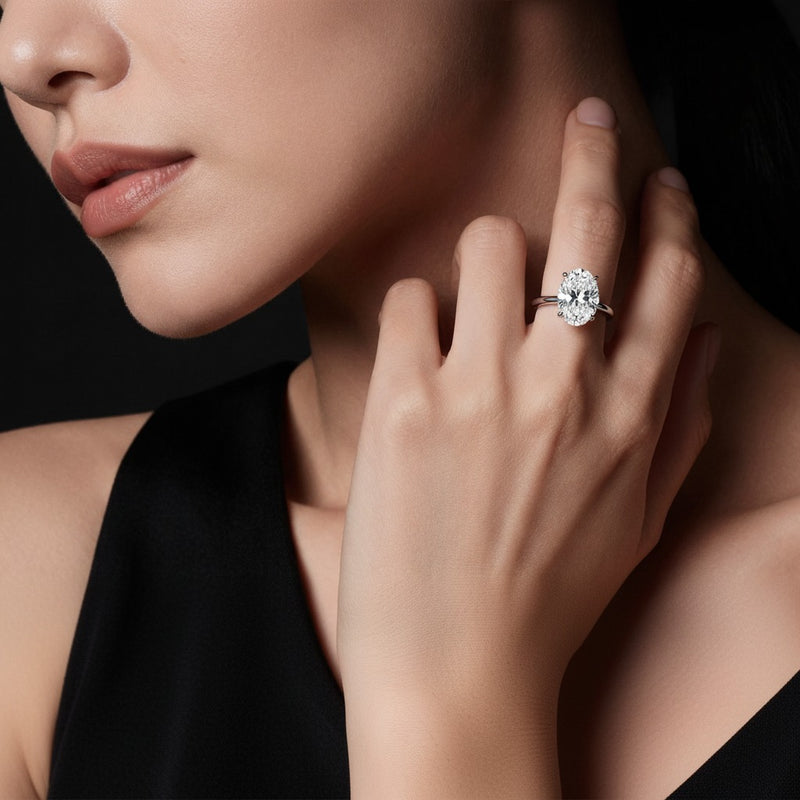 Model wearing oval hidden halo cathedral shank engagement ring