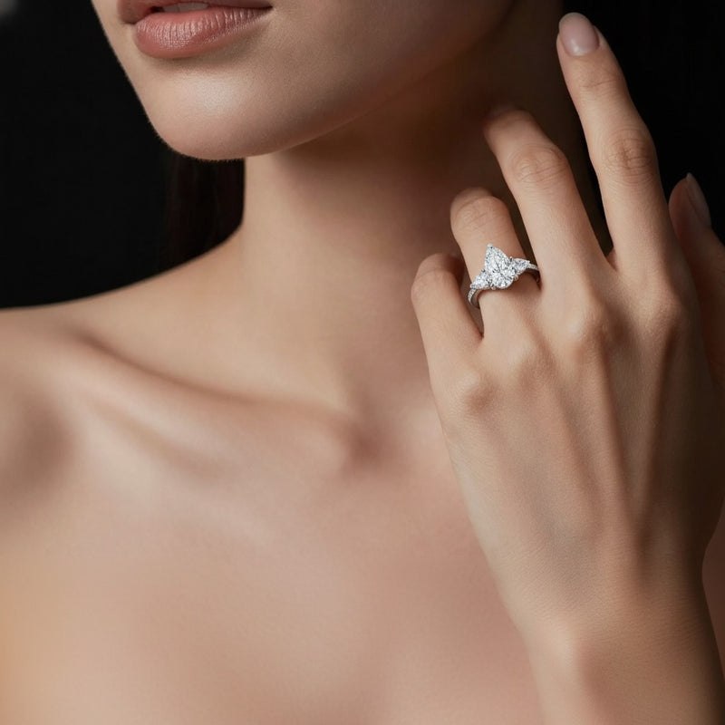 Model wearing pear three stone accented engagement ring