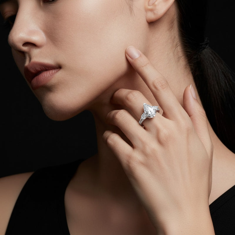 Model wearing pear three stone accented engagement ring