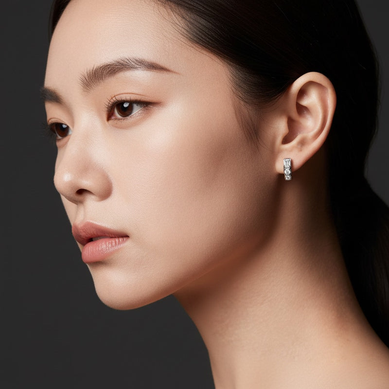 Model wearing emerald three stone huggie earrings