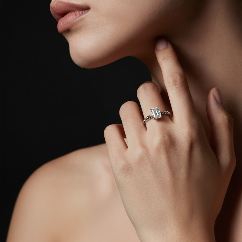 Model wearing emerald petite solitaire engagement ring