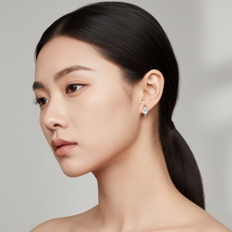 Model wearing oval solitaire huggie earrings