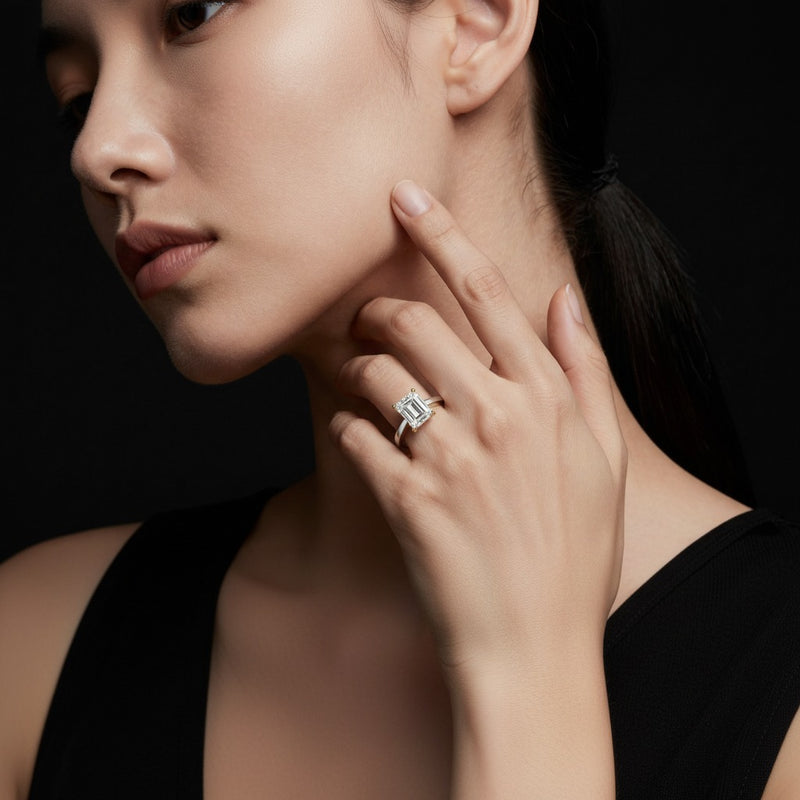 Model wearing emerald two tone twisted basket cathedral shank solitaire ring