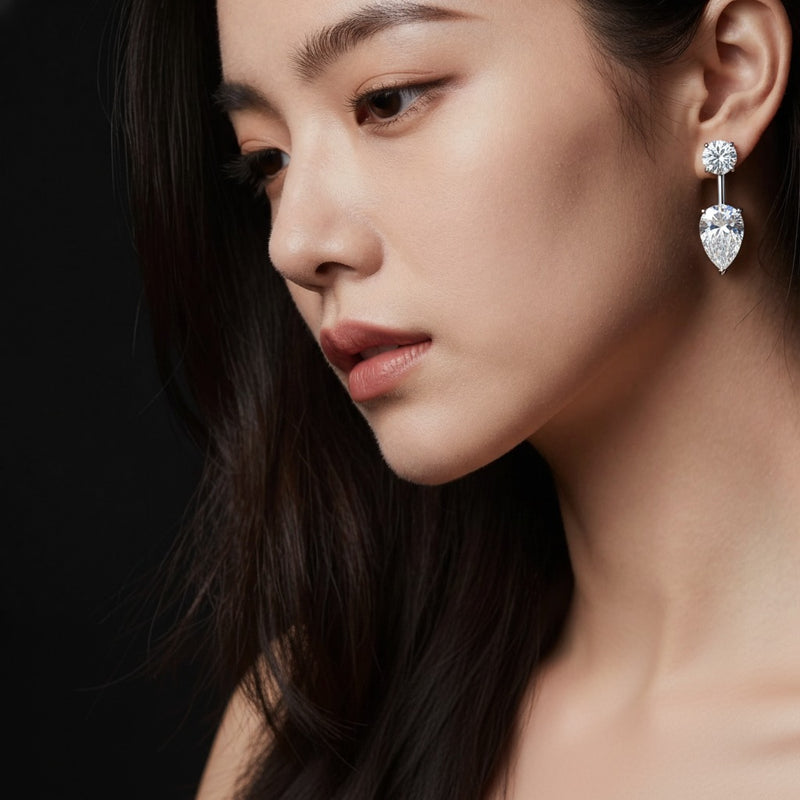 Model wearing pear stud earrings with j hoop earrings