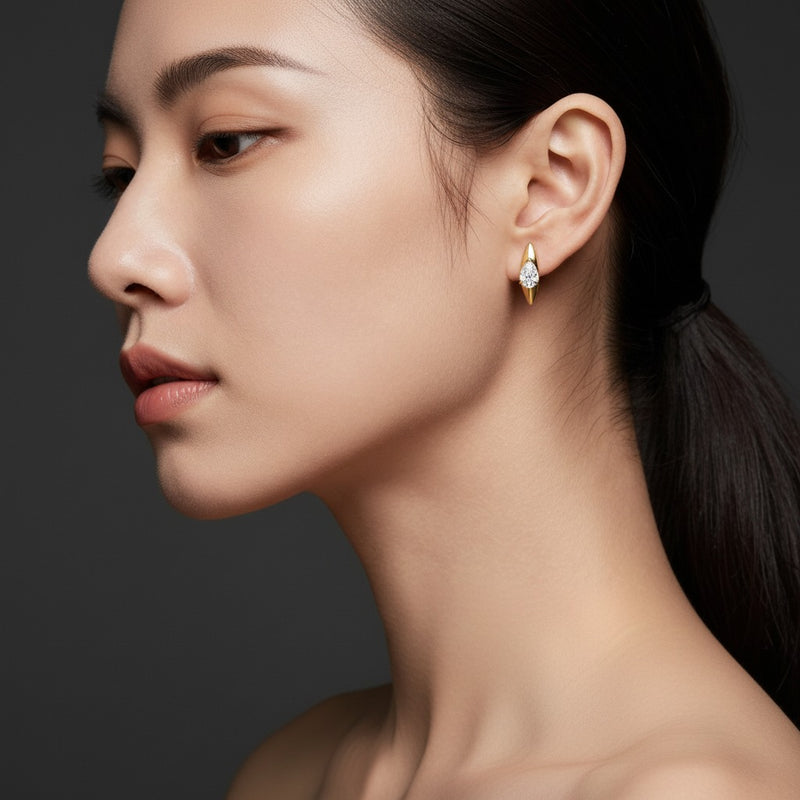Model wearing pear solitaire huggie earrings