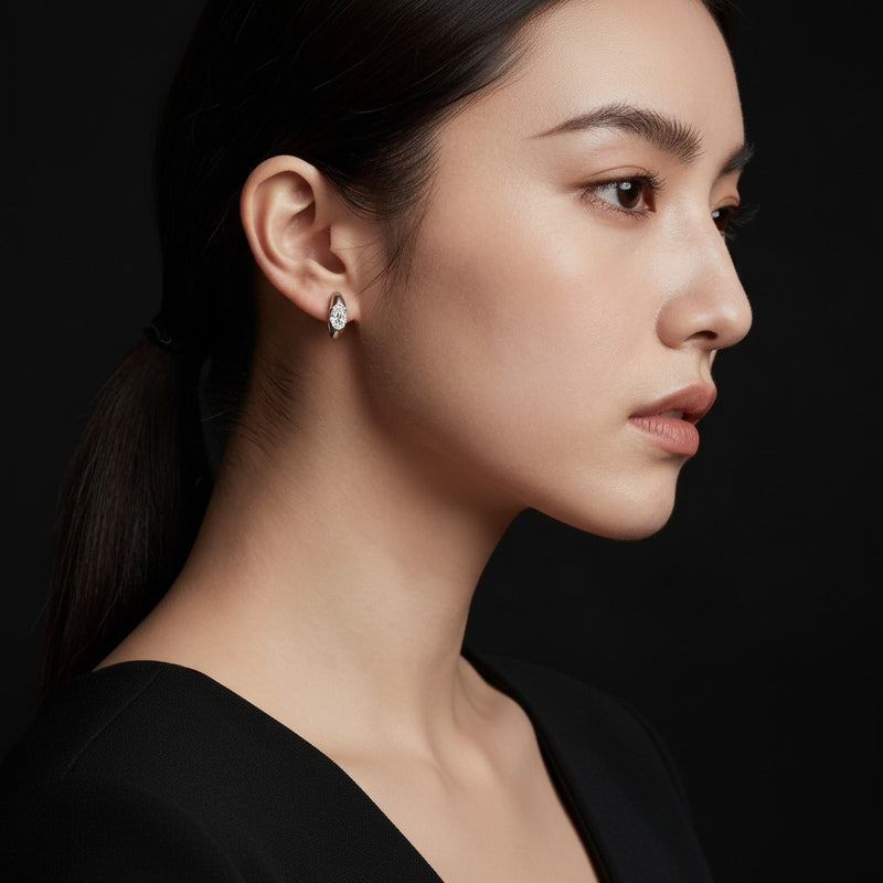 Model wearing oval solitaire huggie earrings
